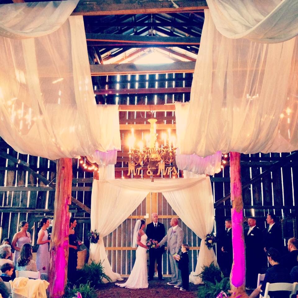 Barn wedding at Drakewood Farm with draped fabric and chandelier